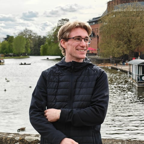 Andre Cox smiling in front of a lake in England